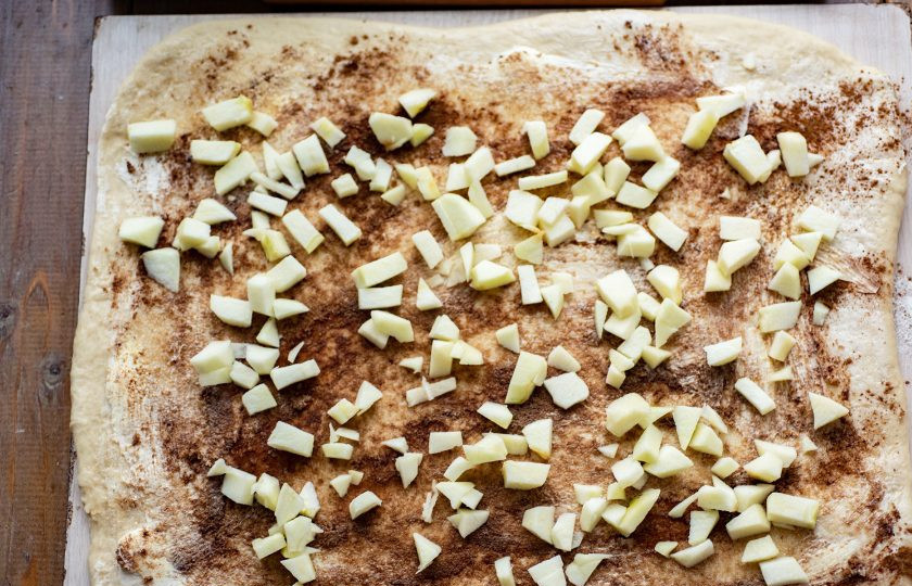 1. Этап. Булочки с яблоком и корицей из дрожжевого теста: Очистите яблоки от кожуры и семян, нарежьте небольшими кусочками. Яблочные кусочки распределите равномерным слоем поверх корицы и сахара.