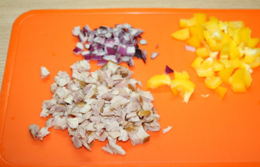 1. Этап. Рисовый салат на Новый год Свиньи: Перец, лук и курицу нарежьте кубиками.