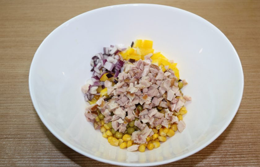 1. Этап. Рисовый салат на Новый год Свиньи: Соедините зелёный горошек, кукурузу, курицу, лук и перец. Добавьте немного майонеза и перемешайте.
