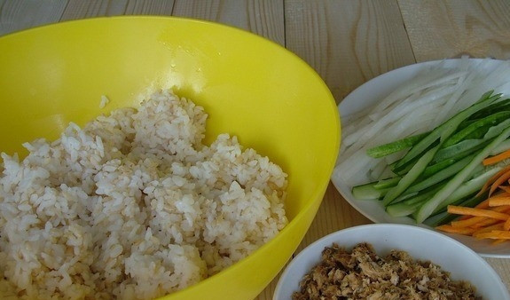 1. Этап. Роллы с тунцом консервированным: 1. Перед тем как приготовить роллы с тунцом консервированным, смешайте круглозернистый и коричневый рис. Промойте рис до появления абсолютно прозрачной воды. Залейте его холодной водой в пропорции 1:2. Доведите до кипения. Сделайте медленный огонь. Отварите под крышкой в течение десяти минут. Снимите с огня. Влейте кунжутное масло. Снова накройте крышкой, дайте постоять до остывания. В это время нарежьте тонкими полосками огурец, морковь и дайкон.