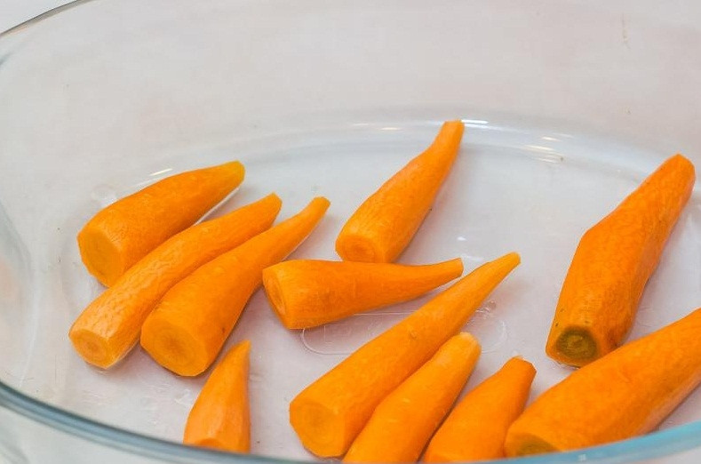 1. Этап. Фаршированные куриные окорочка в духовке: 8. Молодую морковь очищаем и выкладываем в форму для запекания.