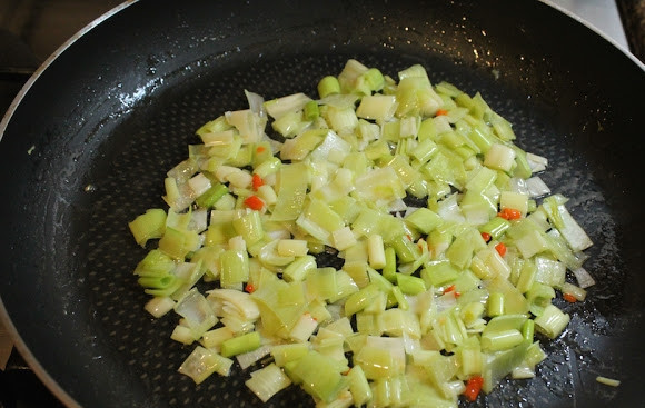 1. Этап. Пирожки с сюрпризом: 2. Разогрейте на сковороде немного сливочного масла. Выложите порей, обжарьте пару минут, помешивая. Добавьте измельченный острый перец по вкусу.