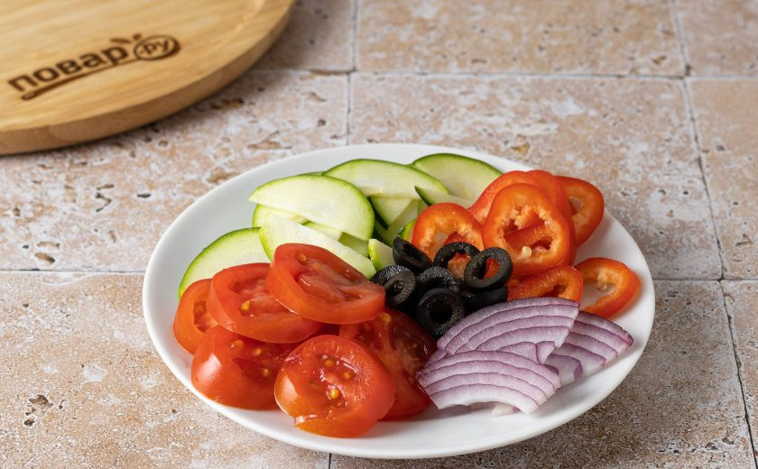 1. Этап. Овощная пицца: Нарежьте тонкими ломтиками цукини, красный лук и перец Рамиро. Помидоры черри и маслины с оливками нарежьте кружочками.