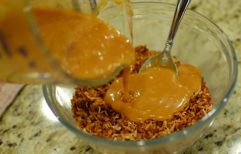 1. Этап. Пирог с ирисками и кокосом: 6. Переложите кокосовую стружку в емкость и залейте растопленными ирисками, перемешайте.