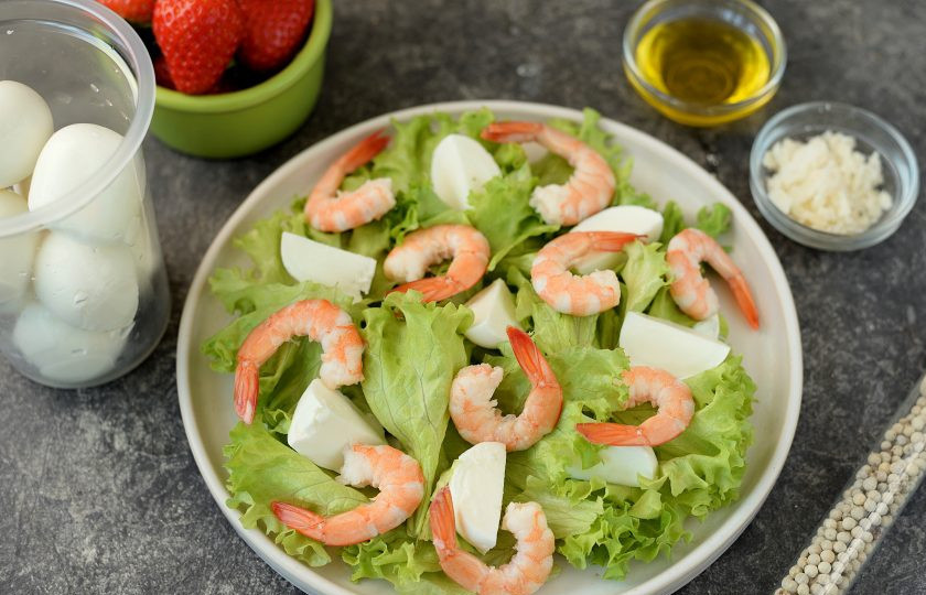 1. Этап. Салат с креветками и клубникой: Латук порвите руками, выложите на плоское блюдо, сверху разложите креветки и нарезанную четвертинками или кружочками моцареллу.