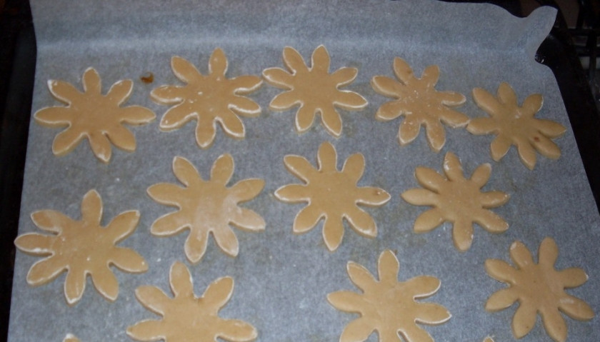 1. Этап. Рождественское печенье с имбирем: Через пару часов достаньте тесто из холодильника, выложите его на рабочую поверхность. Раскатайте его в пласт толщиной в полсантиметра. Если он будет слишком толстый, то ваше печенье будет больше похоже на пряники. Вырежете из теста фигурки, выложите их на застеленный пергаментом противень.