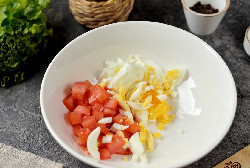 1. Этап. Салат с морепродуктами и красной икрой: Нарежьте крупный помидор средним кубиком, порубите яйцо, переложите в глубокую миску.