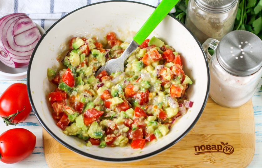 1. Этап. Гуакамоле с помидорами: Аккуратно вилкой перемешайте содержимое емкости с небольшим нажимом, пюрируя половину нарезки авокадо.