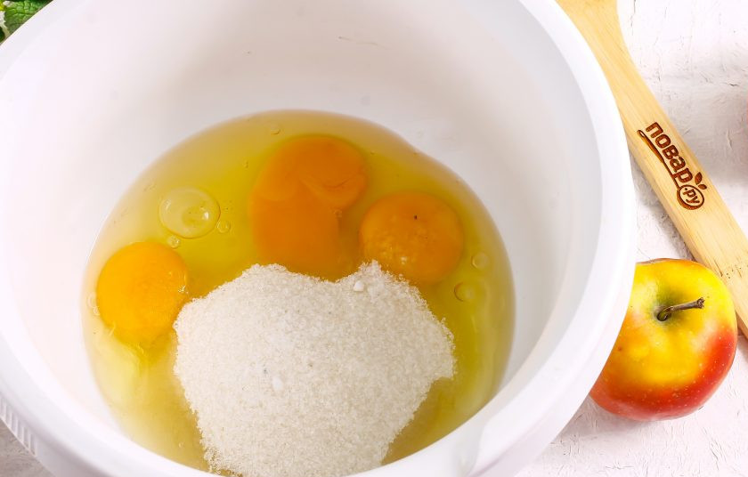 1. Этап. Шарлотка из кукурузной муки: Вбейте куриные яйца в чашу блендера или кухонного комбайна. Всыпьте туда же сахар и соль. Тщательно взбейте все содержимое емкости примерно 3-5 минут до побеления массы и ее увеличения в два-три раза.