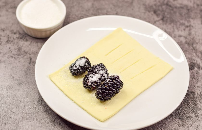 1. Этап. Слойки с ежевикой: Посыпьте ягоды ежевики немного сахарным песком.