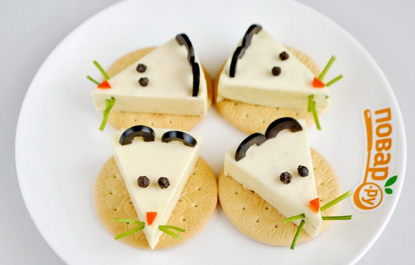 1. Этап. Мышки на крекерах: 3. Оливки порежьте колечками не слишком тонко, чтобы они стояли на сыре, потом каждое колечко на половинки. Поставьте ушки. Из перца сделайте глазки. Из красного перца сделайте треугольнички для носиков.