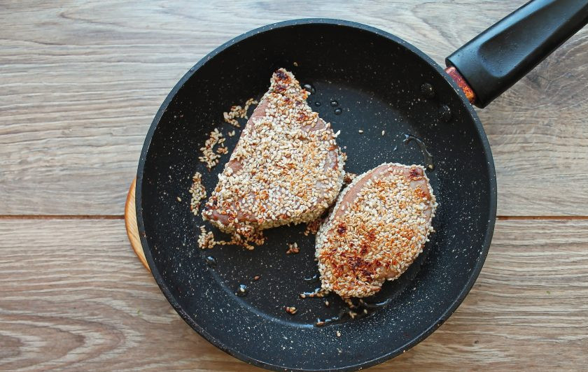 1. Этап. Стейк из тунца в кунжуте: Сухую сковороду разогрейте на среднем огне и обжарьте стейки тунца по 1-2 минуты с каждой стороны. Снимите стейки с огня, порежьте на кусочки под углом 45 градусов и подавайте к столу.