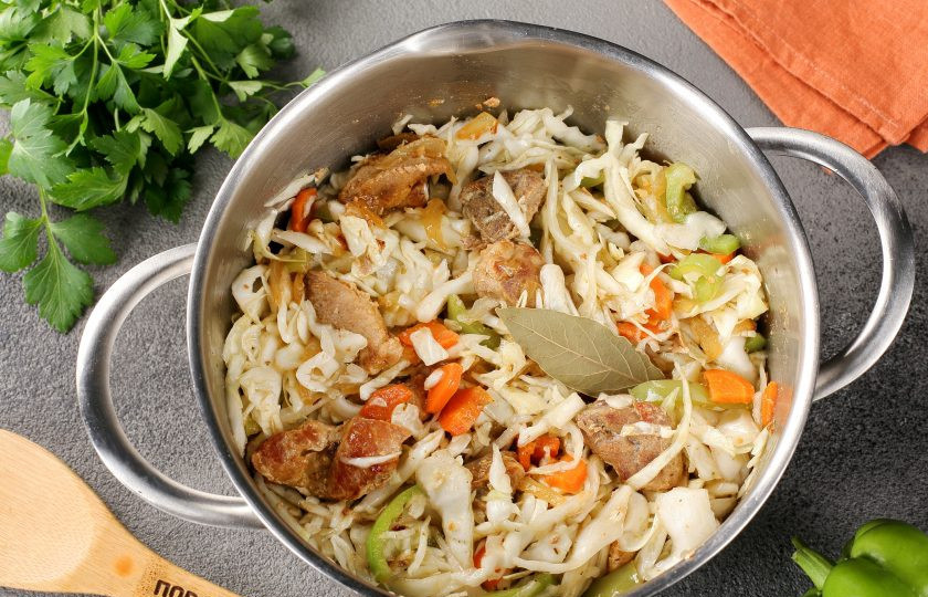 1. Этап. Тушёная капуста с мясом в кастрюле: Переложите капусту в кастрюлю, добавьте соль, сахар, лавровый лист и содержимое сковороды. Влейте 50-100 мл. воды, перемешайте и тушите на небольшом огне до желаемой степени готовности капусты.