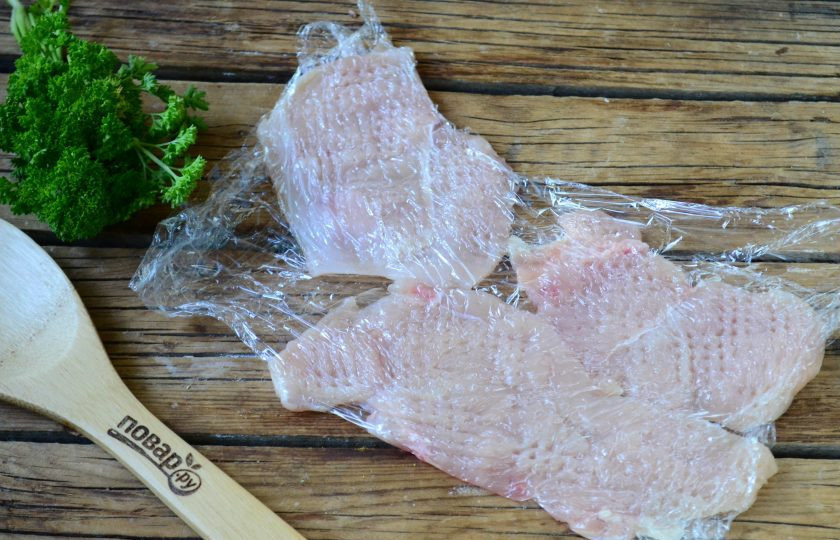 1. Этап. Чипсы из куриного филе: Накройте куриные пластины пищевой пленкой и отбейте кухонным молоточком. Делайте это аккуратно, чтобы не разорвать отбивные.