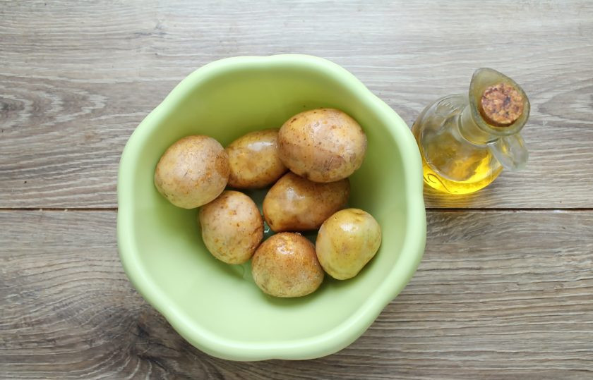 1. Этап. Картошка по-деревенски в микроволновке: Молодой картофель тщательно вымойте мягкой щеткой. Проколите каждый картофель вилкой в нескольких местах, добавьте растительное масло и перемешайте.