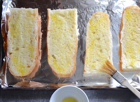 1. Этап. Бутерброды в духовке с грибами и шпинатом: 3. Французский багет разрежьте пополам, затем каждую половинку еще вдоль. Выложите хлеб на противень и смажьте его растительным маслом. Отправьте хлеб на 2-3 минуты в разогретый до 180 градусов духовой шкаф.