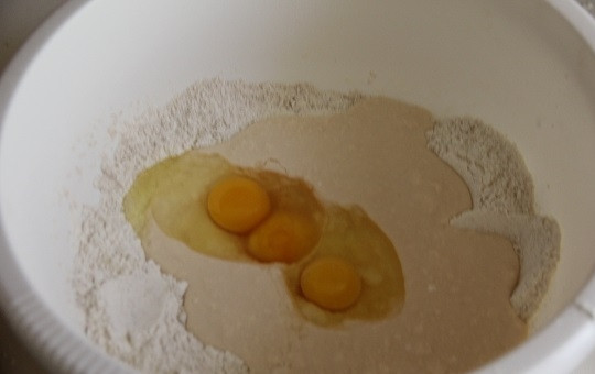 1. Этап. Лепешки на ряженке: 2. Добавьте немного сахара. Вбейте прямо в муку яйца и влейте ряженку. Добавьте просеянный крахмал и начните перемешивать.