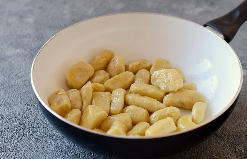 1. Этап. Картофельные ньокки с грибами: В сковороде разогрейте растительное масло, обжарьте ньокки до золотистого цвета. Затем отложите в миску.