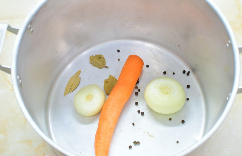 1. Этап. Холодец из рульки и индейки: В просторную кастрюлю выложите очищенный морковь и лук. Добавьте лавровый лист и перец горошком.