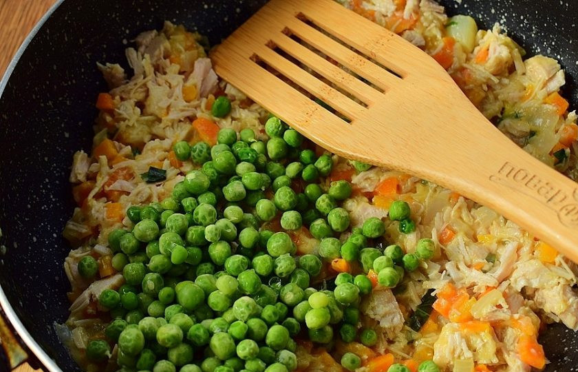 1. Этап. Куриные мини-пироги в горшочках: Добавьте измельченную куриную грудку, зеленый горошек, перемешайте, накройте крышкой, снимите с огня. Начинка должна быть густой, но остаться сочной.