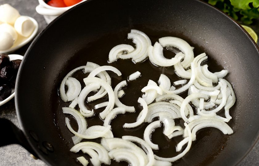 1. Этап. Салат с рапанами: Репчатый лук нарежьте полукольцами, обжарьте на умеренном огне в минимальном количестве растительного масла до мягкого состояния.