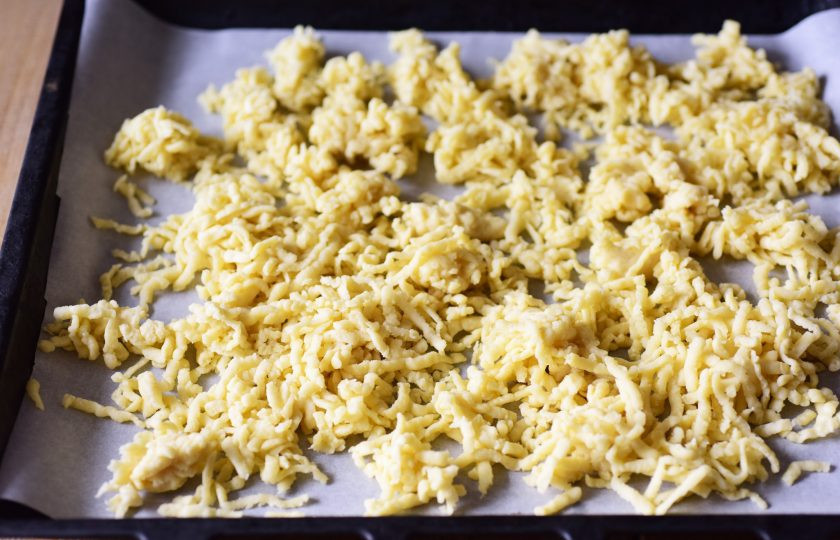 1. Этап. Торт Муравейник с медом: Противень застелите пергаментом для выпекания и выложите равномерным слоем натертое тесто. Выпекайте песочное печенье в уже разогретой до 180 градусов духовке в течение 10-12 минут.