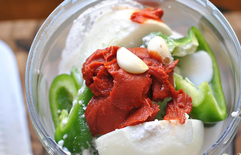 1. Этап. Курица с овощами и кокосовым молоком: 2. Очистить и разрезать лук пополам. Очистить чеснок. Разрезать болгарский перец на 4 части. Смешать лук, чеснок, болгарский перец, томатную пасту, кокосовое молоко, соль, порошок карри и индийские специи в кухонном комбайне до получения однородной консистенции.