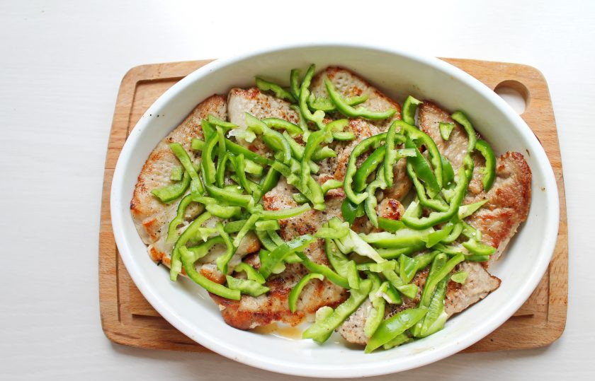 1. Этап. Свинина с маринованными помидорами: Болгарский перец вымойте, удалите плодоножку с семенами и порежьте соломкой. Выложите сверху мясо и поставьте в горячую духовку при температуре 180 градусов на 15 минут.