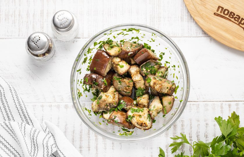 1. Этап. Баклажаны в духовке: Выложите запеченные баклажаны в миску с чесноком и зеленью, поперчите, добавьте винный уксус и перемешайте.