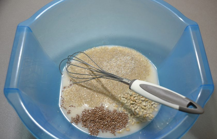1. Этап. Мультизерновой хлеб: В воду комнатной температуры добавьте закваску, прессованные дрожжи, соль, сахар, семена льна, подсолнечника, ржаную крупку. Размешайте до растворения дрожжей, соли и сахара.