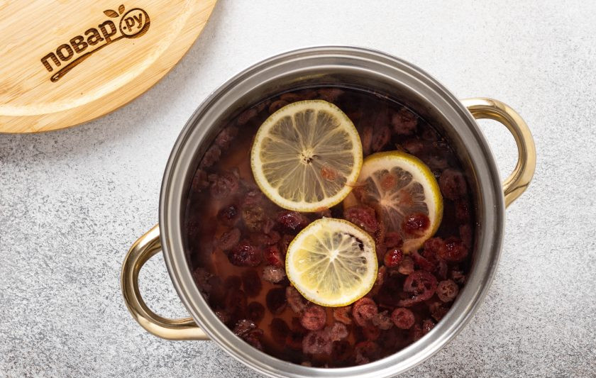 1. Этап. Компот из сушеной клюквы: Лимон промойте, нарежьте кружочками и добавьте в кастрюлю. Варите компот 20 минут на медленном огне. Затем накройте крышкой и дайте остыть.