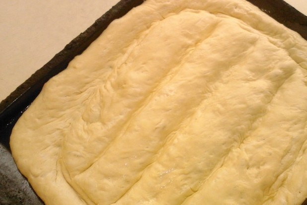 1. Этап. Матнакаш (хлеб по-армянски): Когда тесто немного поднимется на противне, сделайте на нем ребром ладони бороздки (по всему периметру лепешки).