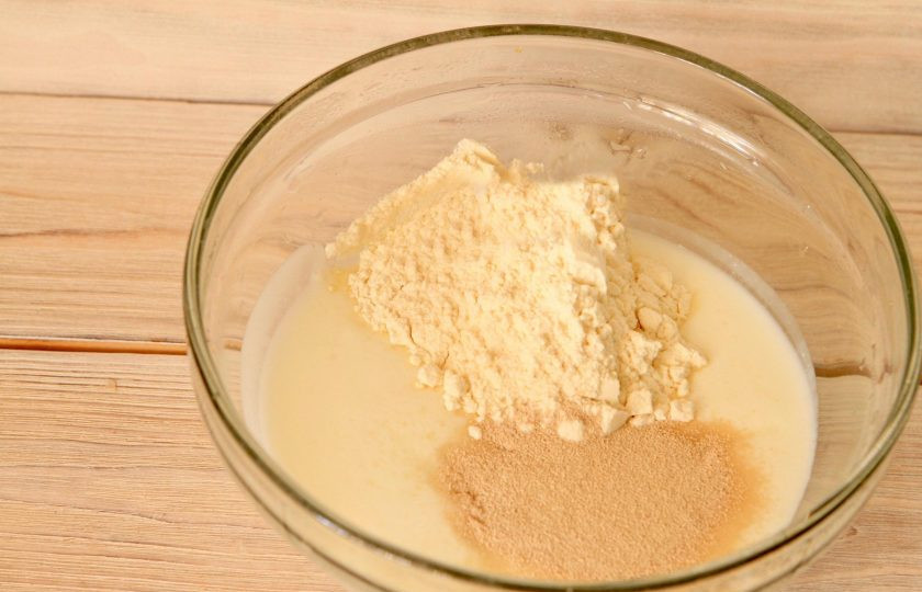 1. Этап. Тесто для пирожков (простой рецепт): В миску просейте муку, влейте половину кефира (комнатной температуры), добавьте дрожжи и сахар. Тщательно перемешайте массу до однородности.