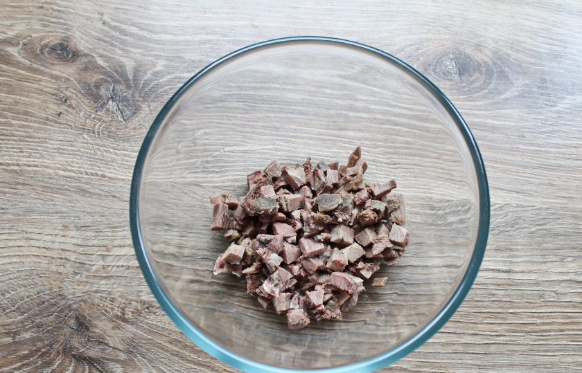 1. Этап. Салат с языком и кедровыми орешками: Отварной язык порежьте средним или мелким кубиком, выложите в миску.