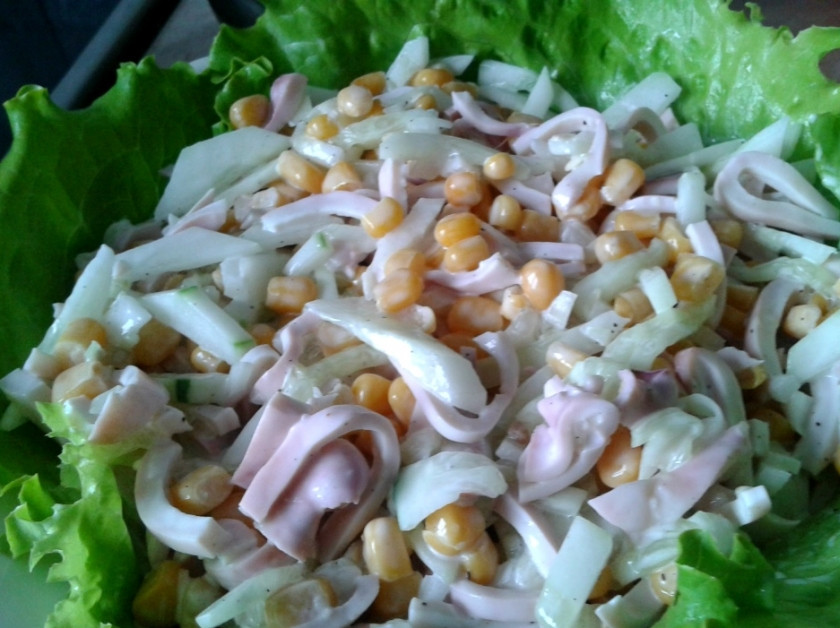 1. Этап. Салат с кальмарами и луком: Добавляем нарезанную тонкими ломтиками ветчину. Открываем баночку кукурузы и сливаем жидкость. Кладем все ингредиенты в миску и сдабриваем майонезом. Кладем на тарелку листья зеленого салата и выкладываем порцию. Салатик из кальмаров с луком, кукурузой и яйцами можно кушать с хлебушком, а также с гречкой и рисом. Приятного аппетита!