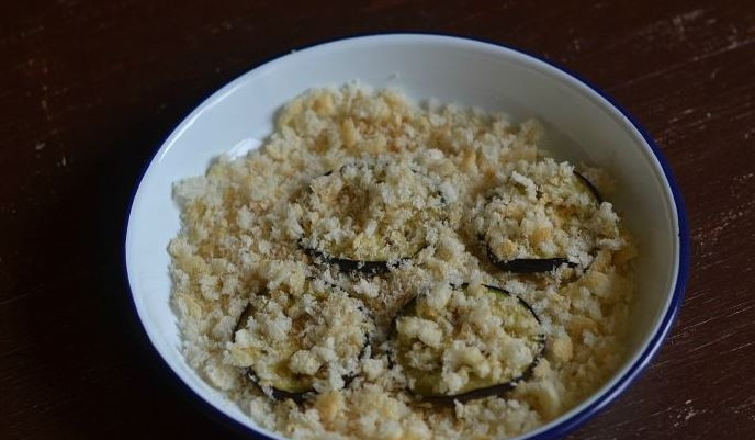 1. Этап. Баклажаны, запеченные с чесноком: Хлеб превратите в крошку при помощи блендера. Также можно использовать уже готовые панировочные сухари. Обмакните в хлеб или сухари кружочки баклажана с обеих сторон.