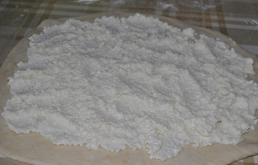 1. Этап. Завитушки с творогом в сметанной заливке: Готовое тесто раскатаем, на него выкладываем, равномерно распределяя, нашу творожную начинку. Тесто сворачиваем рулетом и нарезаем кусочками нужной величины.