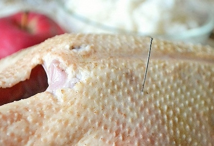 1. Этап. Гусь, фаршированный рисом и сухофруктами: Тушку гуся тщательно моем, удаляем остатки перьев и жир, а также обрезаем первую фалангу крыльев. Дальше с помощью булавки или иголки делаем проколы кожи на грудках и ножках.