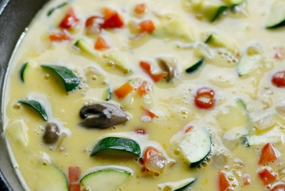 1. Этап. Фриттата с овощами и сыром: 5. После этого в чугунную сковороду выложите все овощи и грибы. Влейте яйца, а также разложите сыр кусочками по всей поверхности.