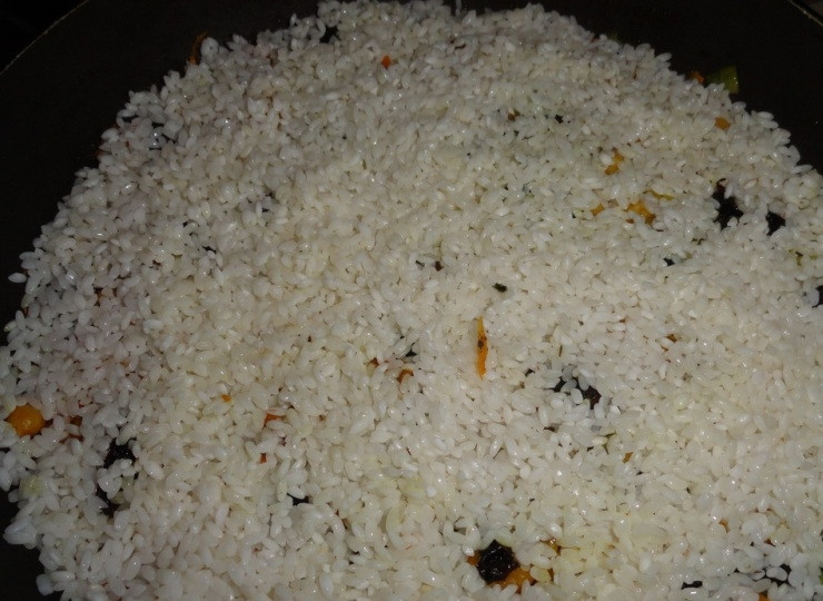 1. Этап. Плов с черносливом: С риса сливаем воды и выкладываем его на сковороду, распределяем равномерно по всему периметру.