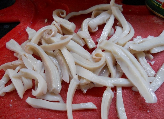 1. Этап. Салат из кальмаров и оливок: Кальмары почистить и сварить. Варятся они в кипящей воде три минуты. Нарезать тонкой соломкой.