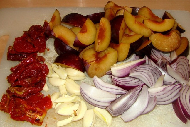 1. Этап. Баранина на кости тушеная: Затем порежьте овощи и фрукты разными способами. Сливы очистите от косточек, разрежьте каждый фрукт на восемь частей. Красный лук нарежьте крупными кольцами, а светлый измельчите любым удобным способом. Одну половину чеснока мелко порубите, вторую нарежьте дольками. Томаты порубите произвольно.