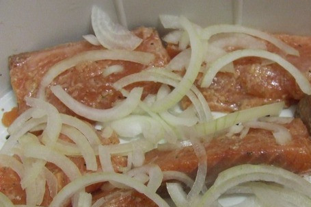 1. Этап. Кета в пароварке: Натираем на мелкой терке морковь. Лук режем полукольцами. Кладем рыбу в пароварку, сверху - лук.