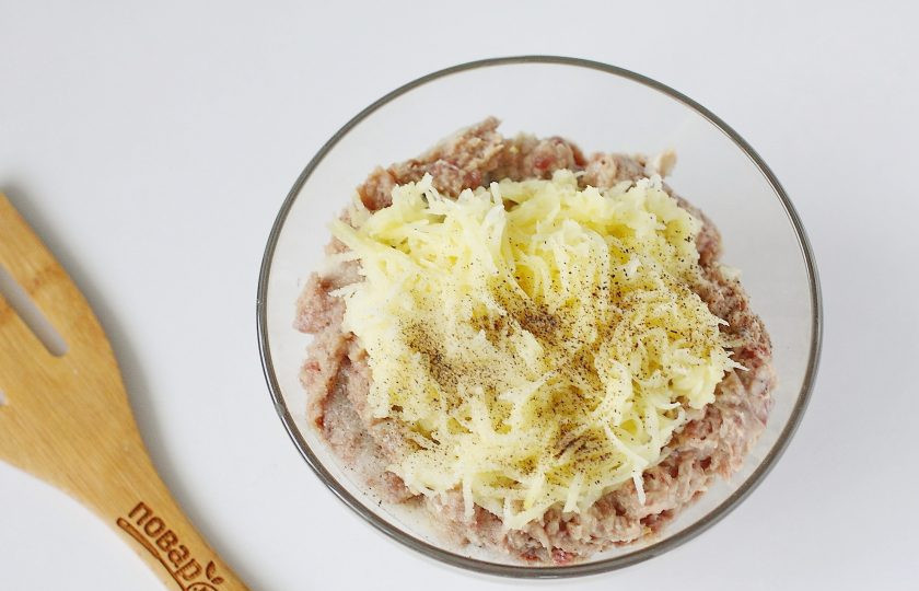 1. Этап. Котлеты из куриных ножек: Переложите готовый фарш в глубокую миску и добавьте тертый на мелкой терке сырой картофель. Посолите все и поперчите по вкусу. Можно добавить любимые специи.