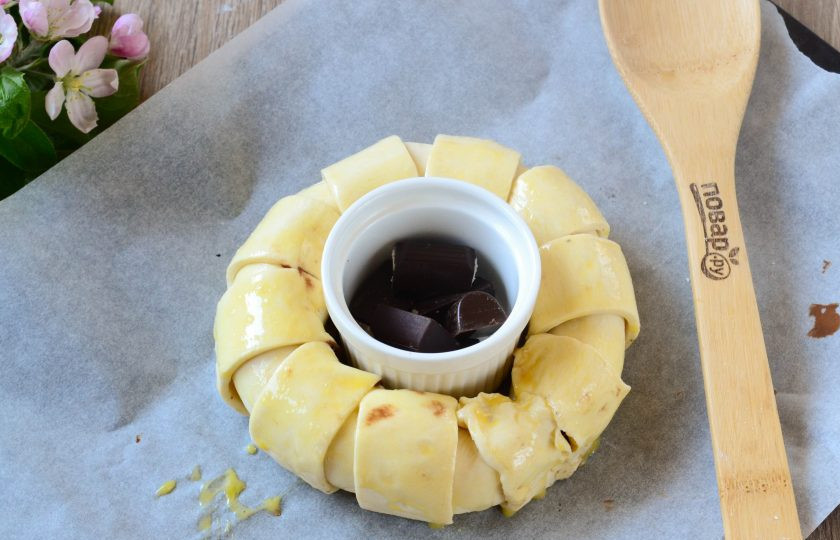 1. Этап. Шоколадное кольцо: В середину рулета поставьте небольшую формочку для запекания или пиалочку, в которую положите кусочки шоколада. Само шоколадное кольцо смажьте взбитым яйцом.