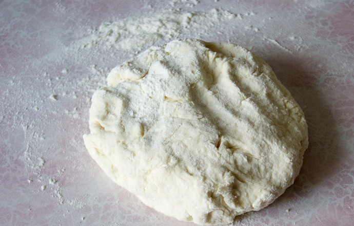 1. Этап. Творожные пирожки с яблоками и изюмом: Смешаем творог, яйца и сметану вместе до однородности. Муку в отдельном стакане (или миске) смешайте с разрыхлителем и солью. Смешайте творожную массу с мукой, замешивая плотное эластичное тесто. Только не перебарщивайте с мукой, лучше чуть сильнее присыпать стол при раскатывании.