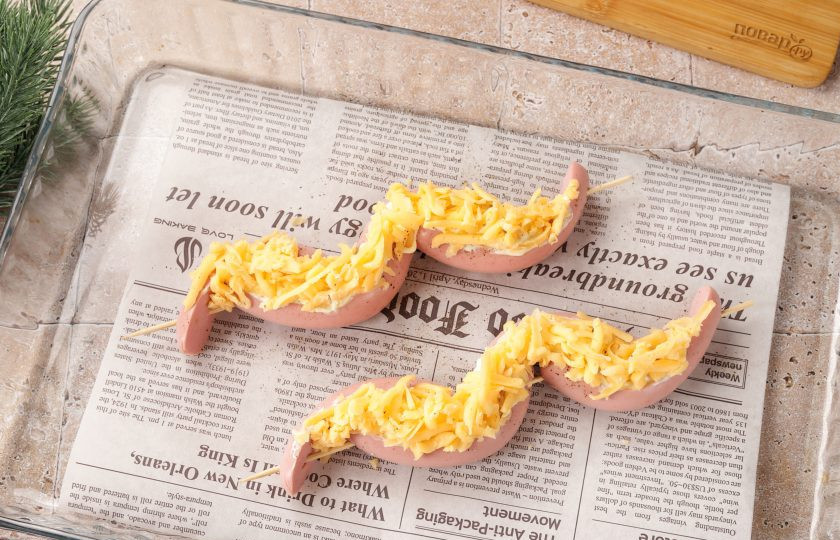 1. Этап. Закусочные Змейки из сосисок с помидорами и сыром: Смажьте верх майонезом или любым другим соусом по вкусу и посыпьте всё тёртым сыром.