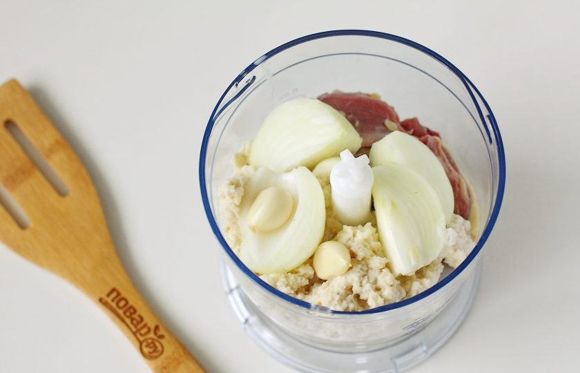 1. Этап. Котлеты из куриных ножек: Добавьте сюда же нарезанную на части очищенную луковицу, замоченный в молоке хлеб и зубчики чеснока.