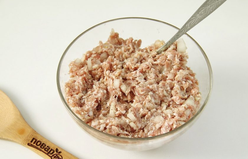 1. Этап. Мясные шарики в слоеном тесте: Переложите фарш в глубокую миску. Добавьте к нему измельченную луковицу, пропущенный через пресс чеснок, соль и перец по вкусу. Тщательно перемешайте.