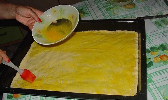 1. Этап. Армянская пахлава: 9. Затем второй пласт теста и оставшаяся начинка. Третий кусочек раскатайте и выложите сверху. Взбейте вилкой желтки и смажьте с помощью кисточки поверхность, чтобы пахлава была румяной.